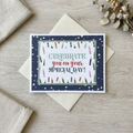Closed Celebrate You mini mounted birthday card with candle border and navy star backing, styled on pale wood with linen.