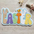 Layered pastel EASTER cardstock scrapbook title with bunny ears, a chick and flower details, styled on pale wood with linen and dried flowers.